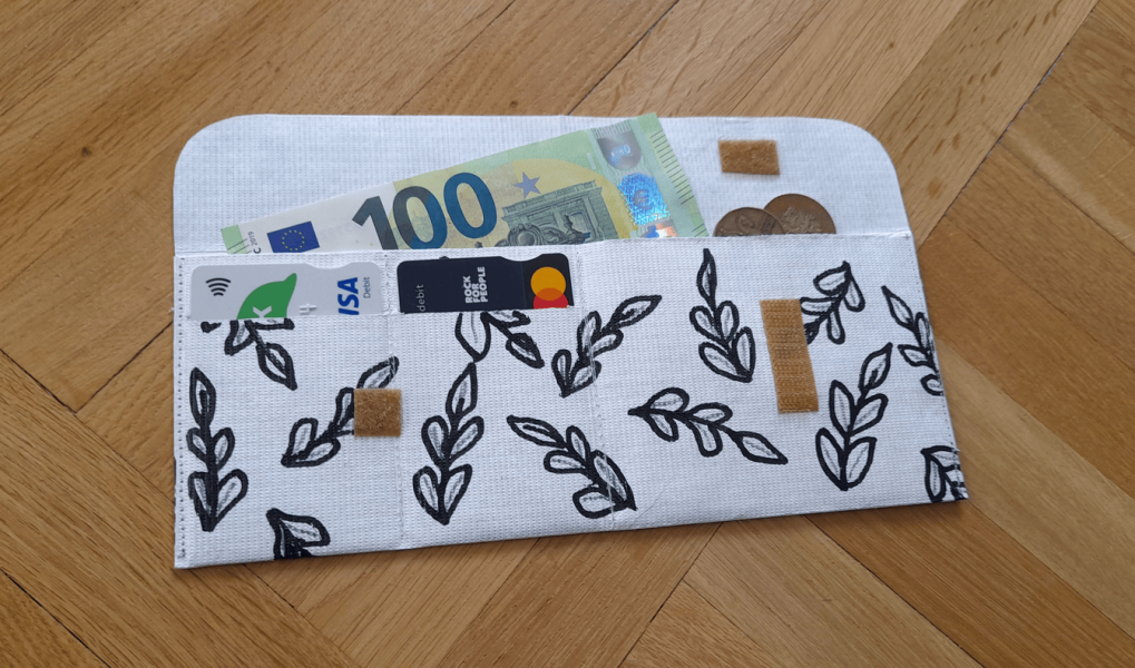 Ultralehká peněženka z Tyveku s čb vzorem lístků, otevřená s penězi a kartami.